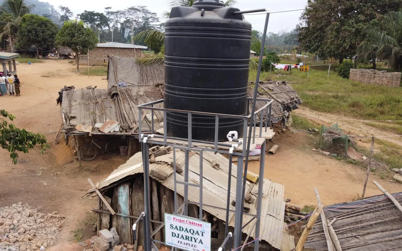 A water tower and its standpipes in the middle of a village