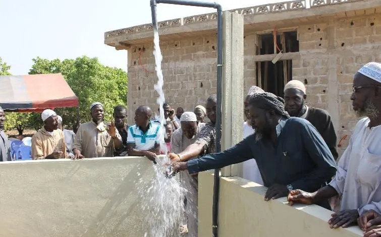 Villagers draw water gushing from a fountain on inauguration day