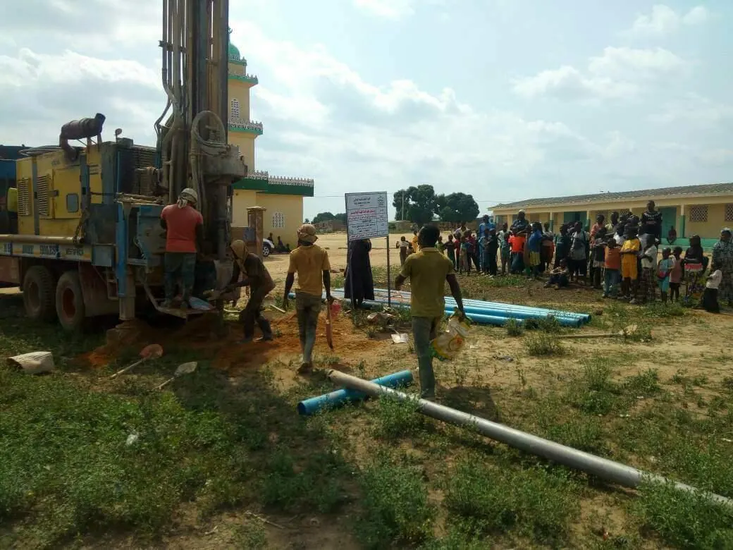 A drilling rig at work in front of villagers