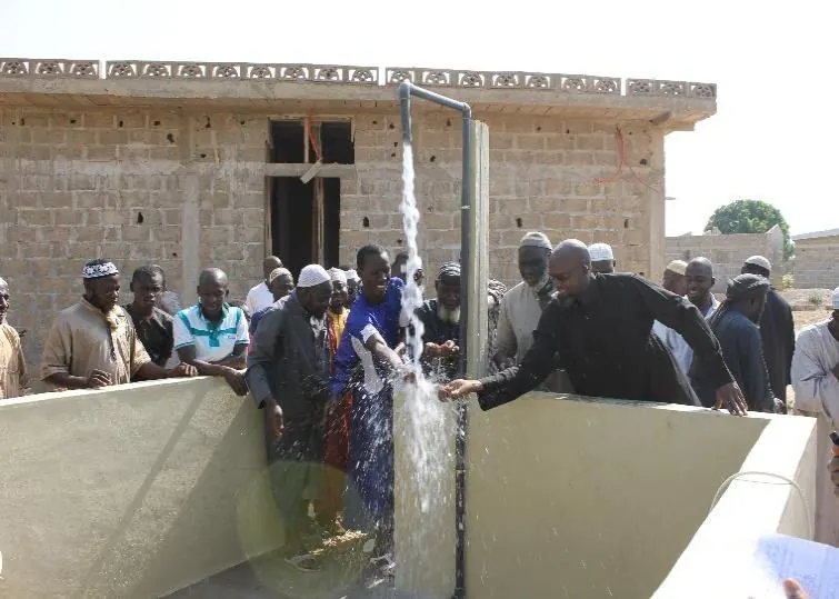 Water flows in front of villagers gathered for the inauguration