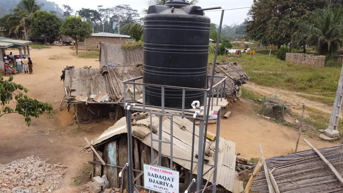 A water tower and its standpipes in the middle of a village